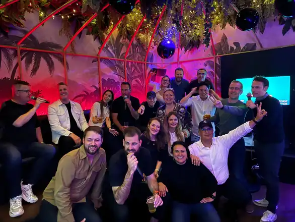 The Fluent Commerce team at a company party, hands in the air for the camera.