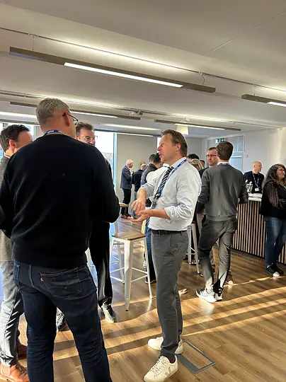 Colleagues in lanyards standing and talking at an office event.