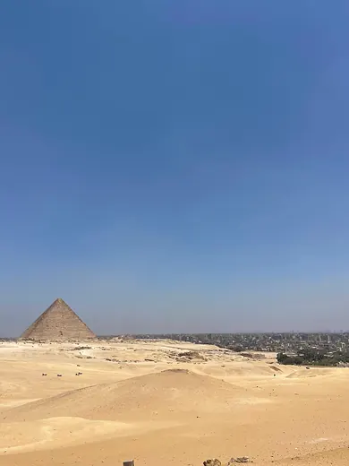 A pyramid at Giza standing over the desert under a clear sky.