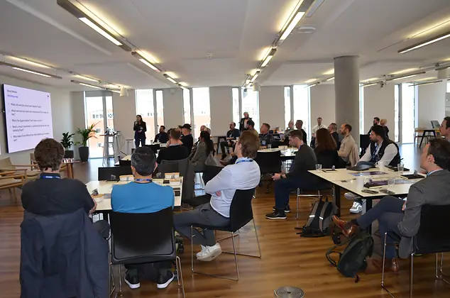 Guests at a Fluent Commerce event, working at long tables in a bright room.