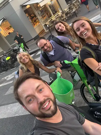 Colleagues crowded into a selfie on hire e-bikes in the street.