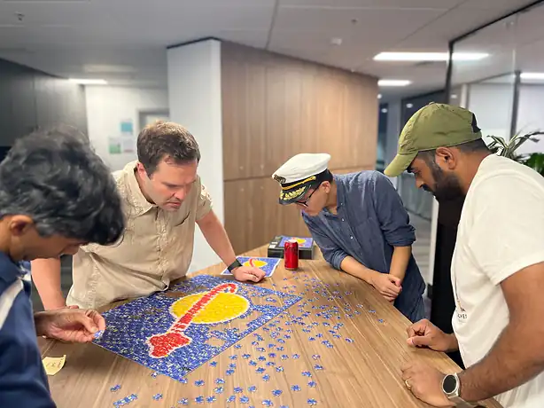 Four colleagues around a table, building a jigsaw together.