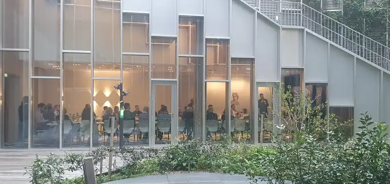 A glass office building lit up at dusk, people at work inside.