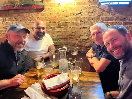 Four colleagues around a pub table, glasses in front of them.