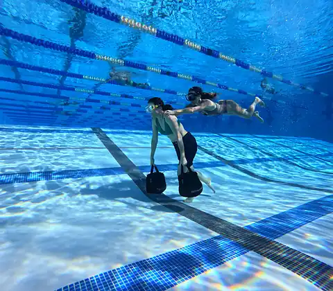Two swimmers underwater in a pool, mid-length.