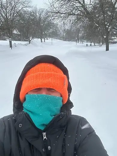 A colleague wrapped up in a bright orange hat in deep snow.
