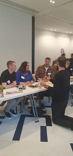Colleagues in name badges talking around a table at a Fluent Commerce workshop.