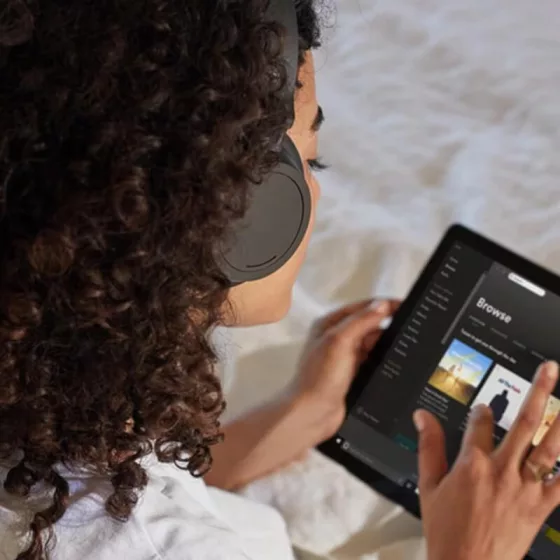 A woman in headphones browsing on a tablet