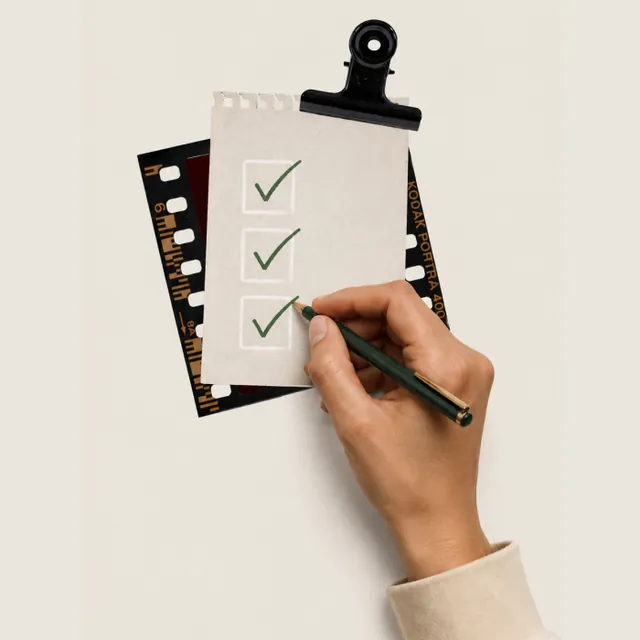 A hand ticking the last box on a paper checklist held under a binder clip