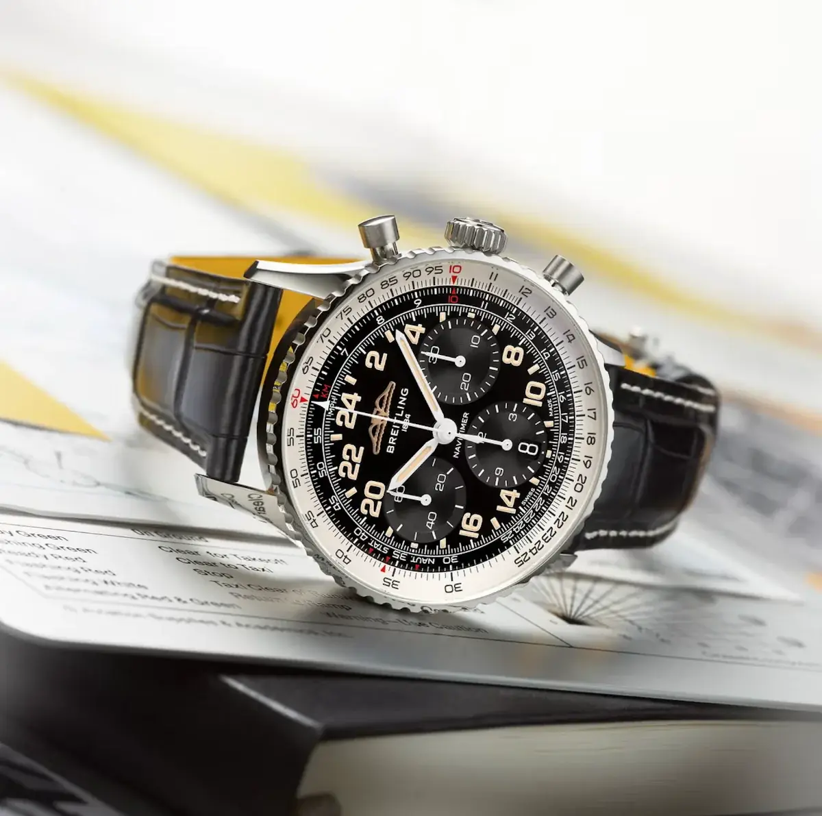 A Breitling Navitimer chronograph resting on aviation navigation charts.